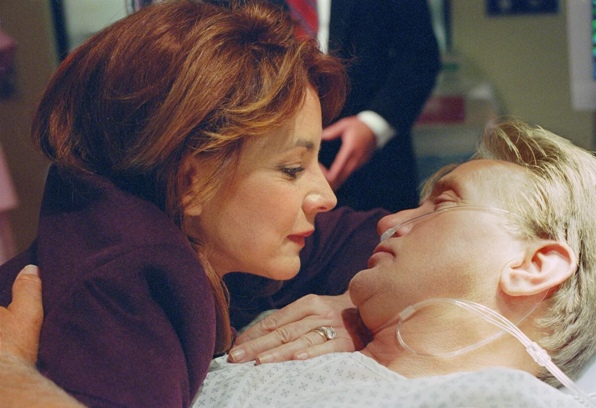 Martin Sheen lies in a hospital bed as Stockard Channing embraces him in "The West Wing."