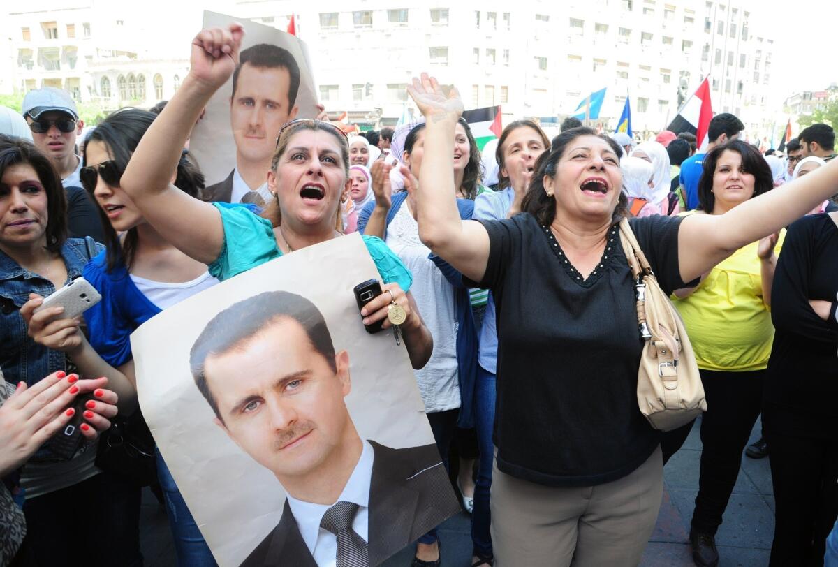Supporters shout slogans and wave portraits of Syrian President Bashar Assad during a rally April 28 backing his bid for a new term in office.