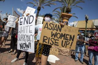ALHAMBRA, CA - MARCH 21: Tina Zeng, 31, of Alhambra, holds two signs as she and other demonstrators gather to speak out and protest racism on Garfield Ave. on Sunday, March 21, 2021 in Alhambra, CA. (Brian van der Brug / Los Angeles Times)