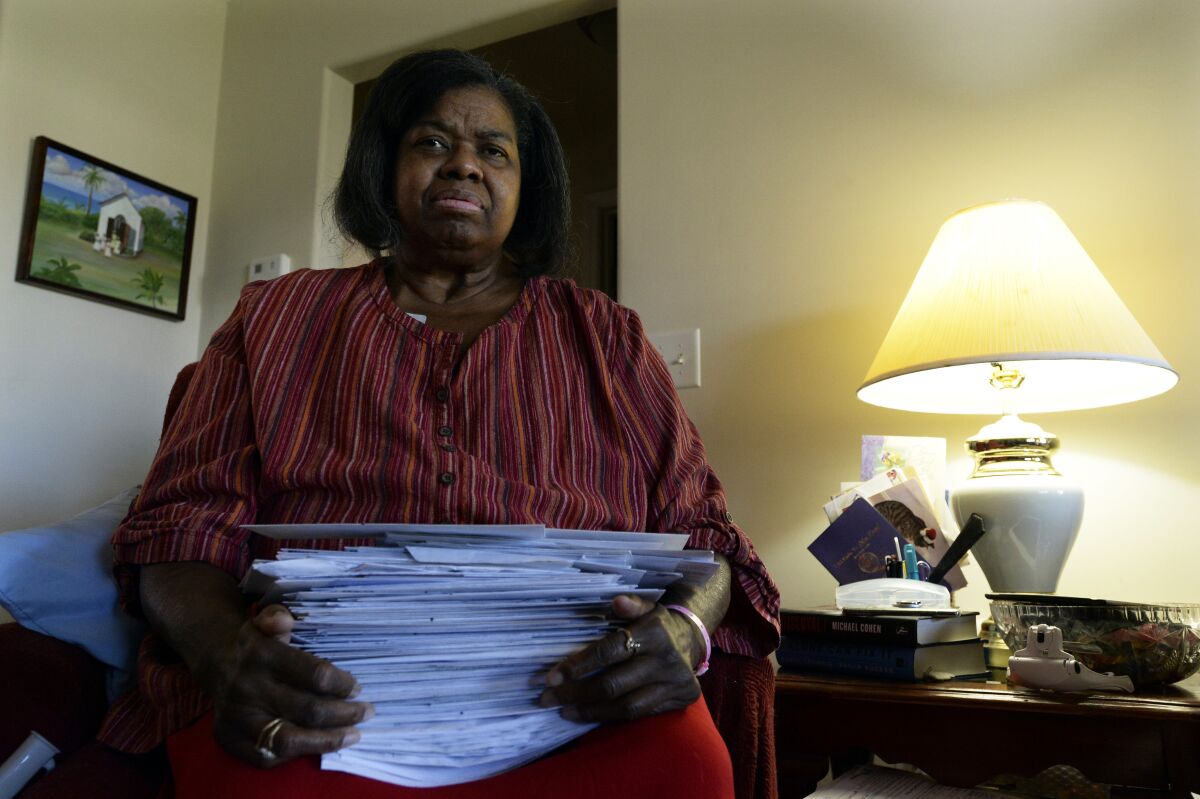 Debra Smith, 57, holds her medical bills in her living room on Thursday, Oct. 7, 2021, in Spring Hill, Tenn. Smith, who has health problems that prevent her from working, has about $10,000 in unpaid medical bills. Living expenses and prescriptions consume most of the $2,300 a month Smith gets from a pension and Social Security. (AP Photo/Mark Zaleski)