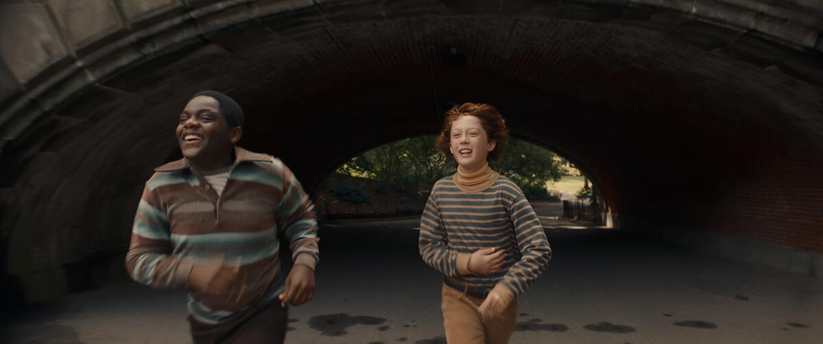 Two young people run from under a bridge, laughing.