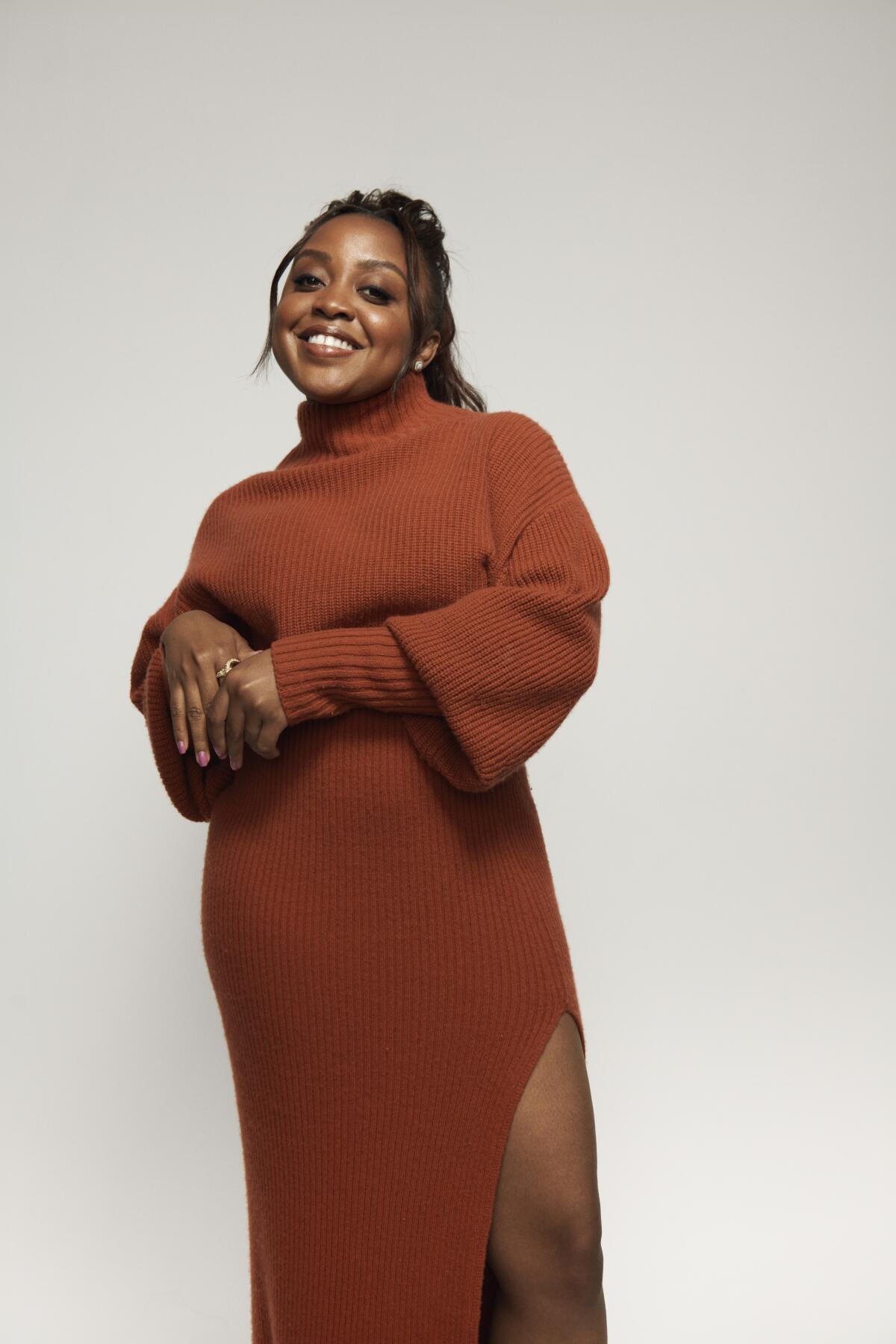 Quinta Brunson poses for a portrait in a sweater dress with a side slit.