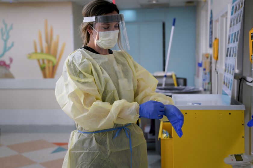 SAN DIEGO, CA - AUGUST 14: Kelsey Nagel a nurse with Rady Children's Hospital puts on PPE, before entering a patient's room at the Special Infectious Disease Unit (SIDU) where one of her patients has tested positive for COVID-19. (Nelvin C. Cepeda / The San Diego Union-Tribune)