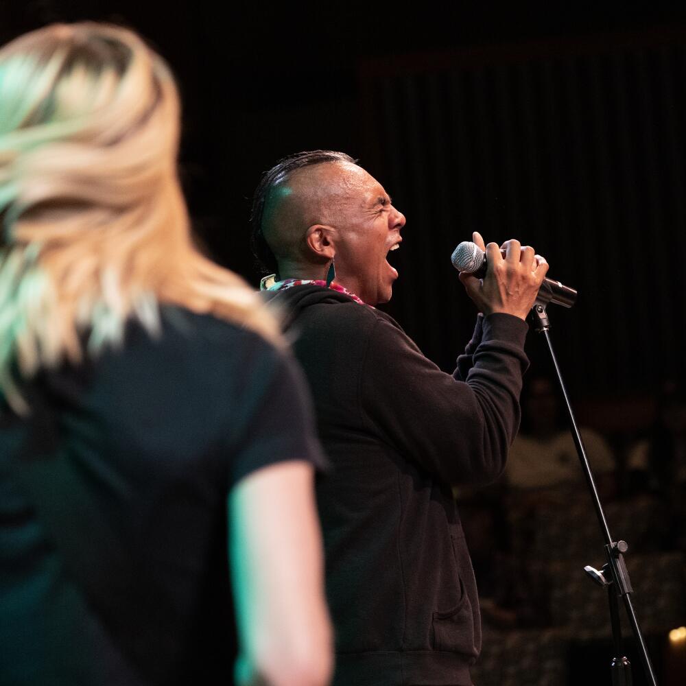 Fontman Antonio Sanchez singing with feeling, clutching a stand-up mic.
