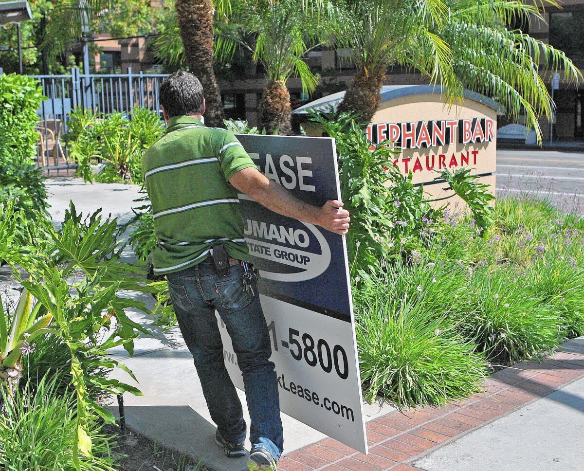 Keith Paul, of Burbank, carries a 'For Lease' sign at recently closed Elephant Bar in Burbank on Tuesday, June 18, 2014. A note on the door apologizes and notes the restaurant is no longer in business.