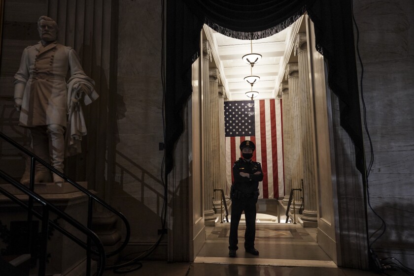 An officer stands near a U.S. flag.