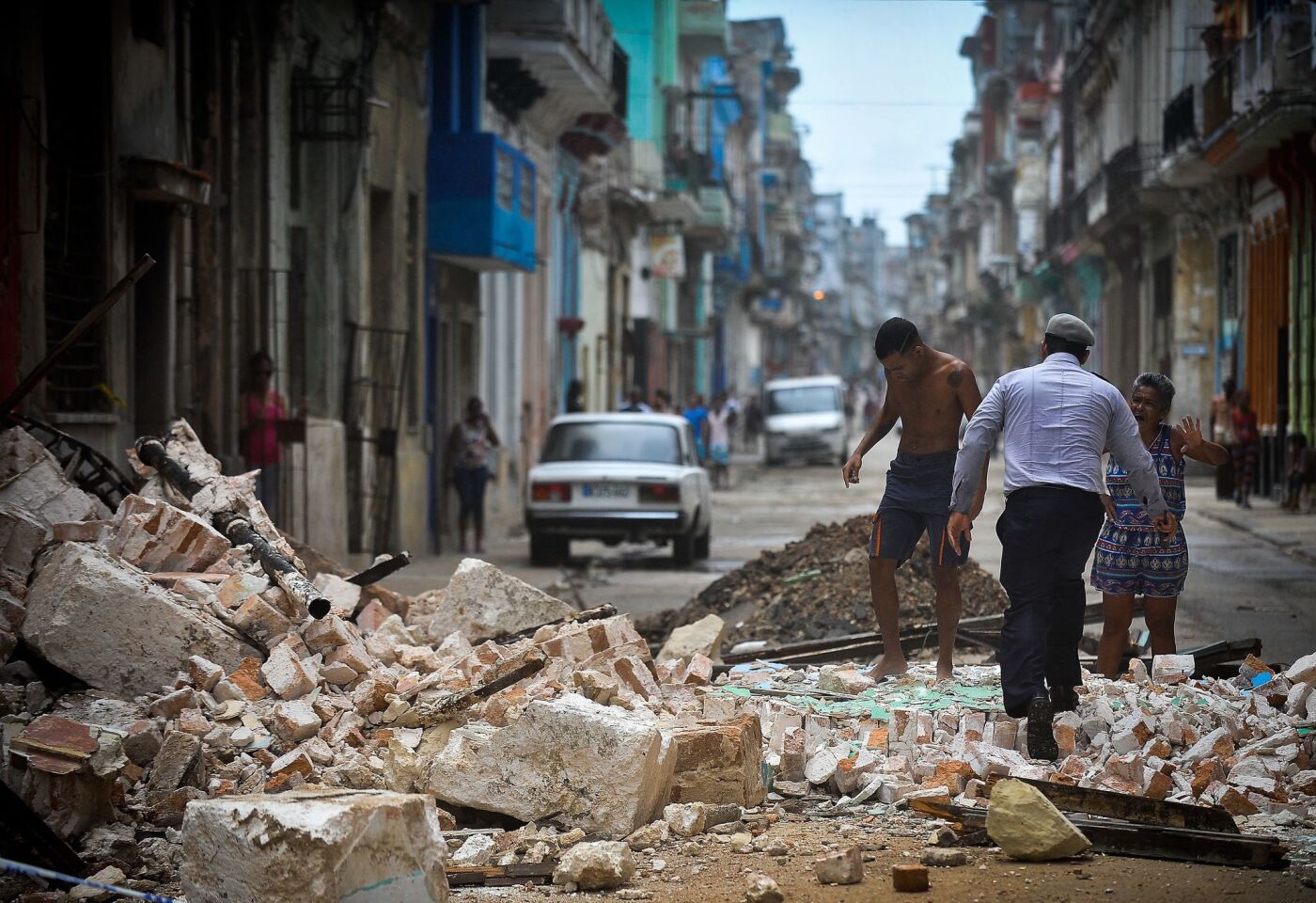 Cubans wade through the rubble from a collapsed building in Havana on Saturday.