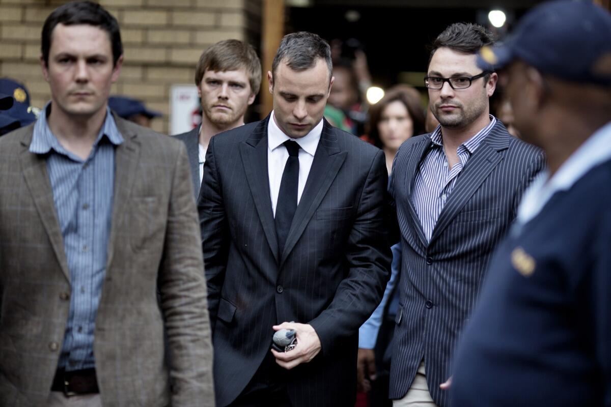 Oscas Pistorius, second from left, leaves the North Gauteng High Court in Pretoria.