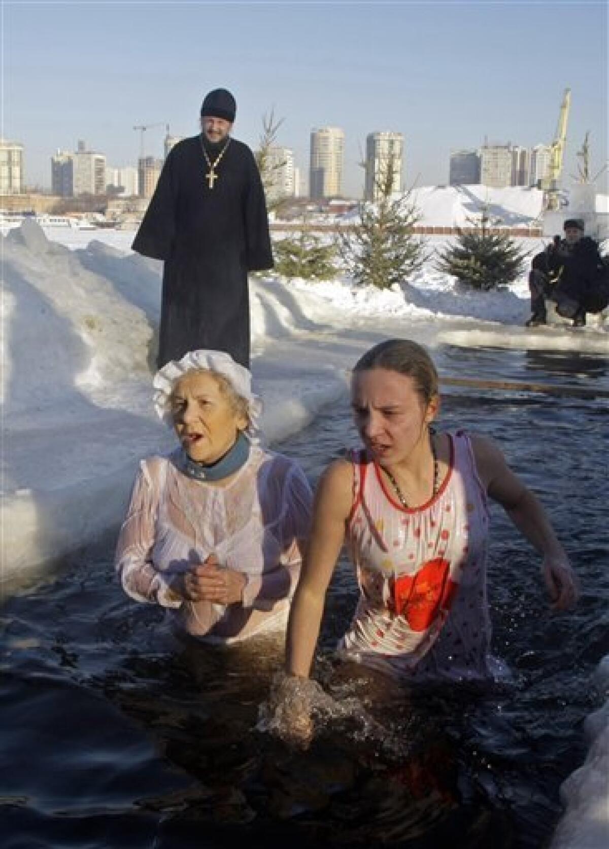 An elderly woman and girl wade into an icy pond to mark the upcoming Epiphany in the northwestern Moscow, Monday, Jan. 18, 2010. Thousands of Russian Orthodox Church followers plunged Monday into icy rivers and ponds across the country to mark the upcoming Epiphany, cleansing themselves with water deemed holy for the day. Water that is blessed by a cleric on Epiphany is considered holy and pure until next year's celebration, and is believed to have special powers of protection and healing. The Russian Orthodox Church follows the old Julian calendar, according to which Epiphany falls on Jan. 19. Moscow temperatures on Monday morning dropped to -20 C (-4 F). (AP Photo/Mikhail Metzel) — AP
