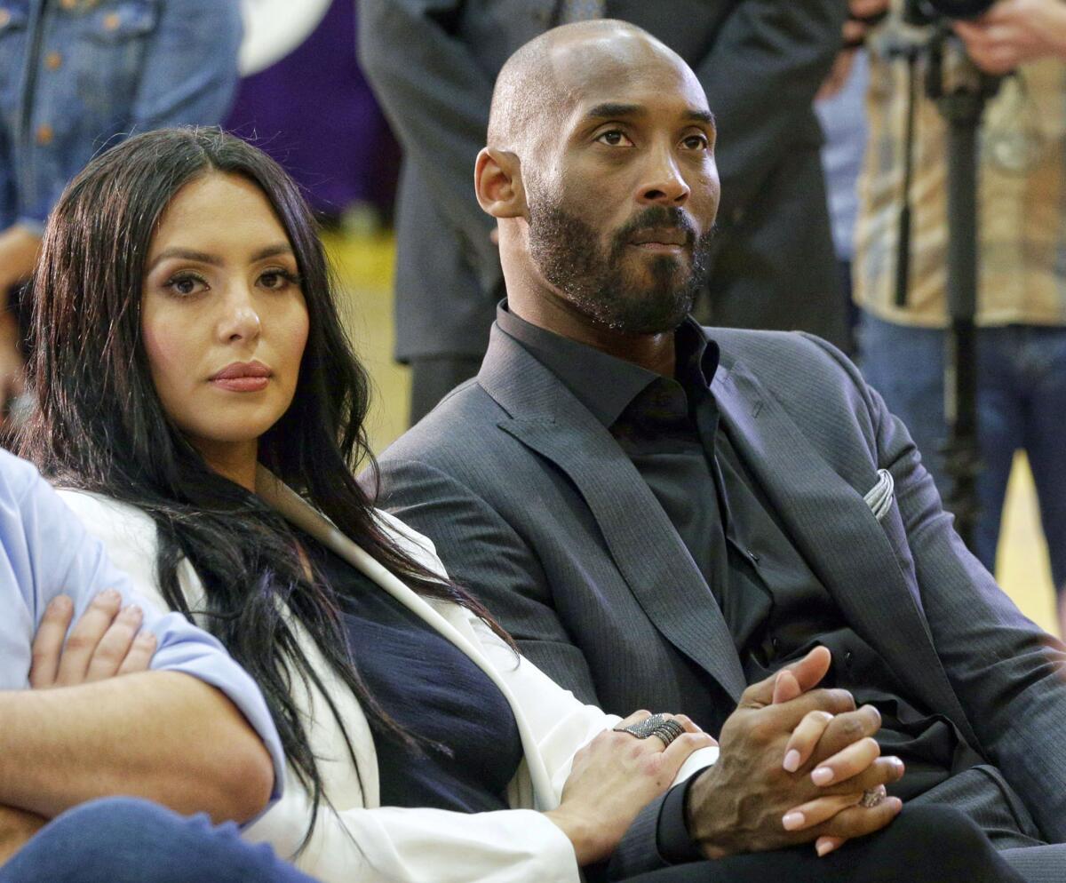 Kobe Bryant and his wife, Vanessa, watch as Rob Pelinka, right, speaks March 10, 2017. 