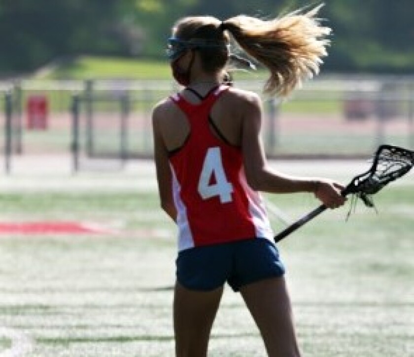 A girl practices with her lacrosse team.