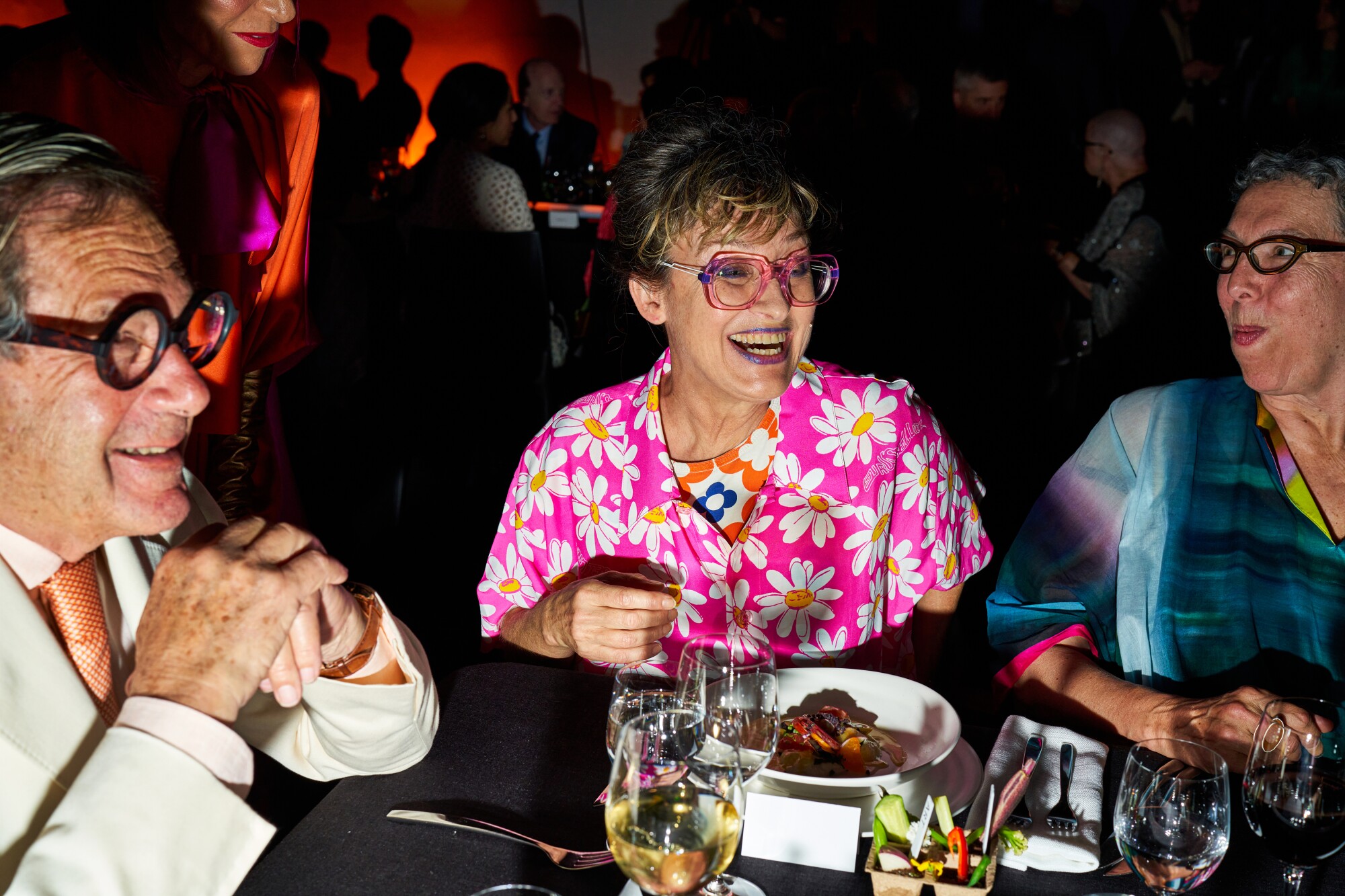 A woman in a colorful outfit and glasses pictured with a man in spectacles.