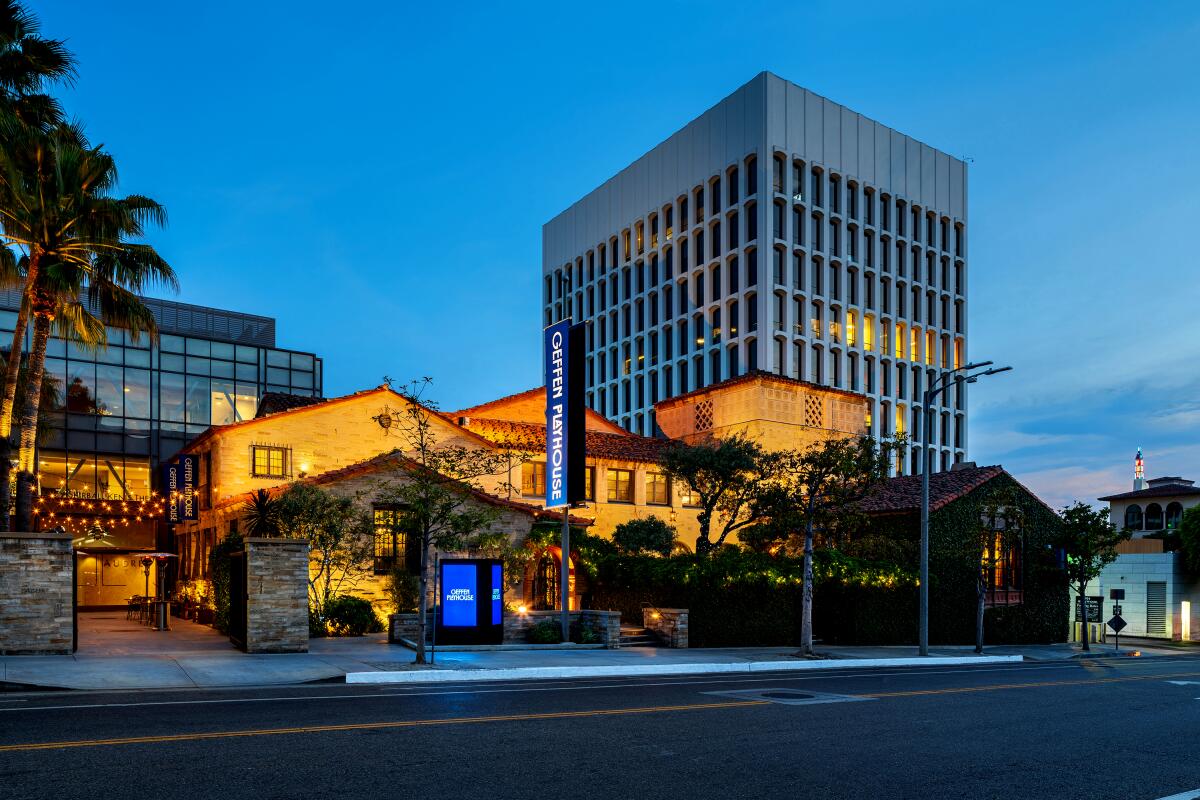 The exterior of a Spanish-style building with brick on the front is seen at dusk. 