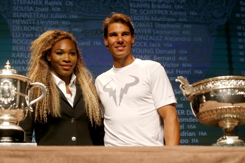 Defending French Open champions Serena Williams and Rafael Nadal pose next to the women's and men's trophies on Friday in Paris.