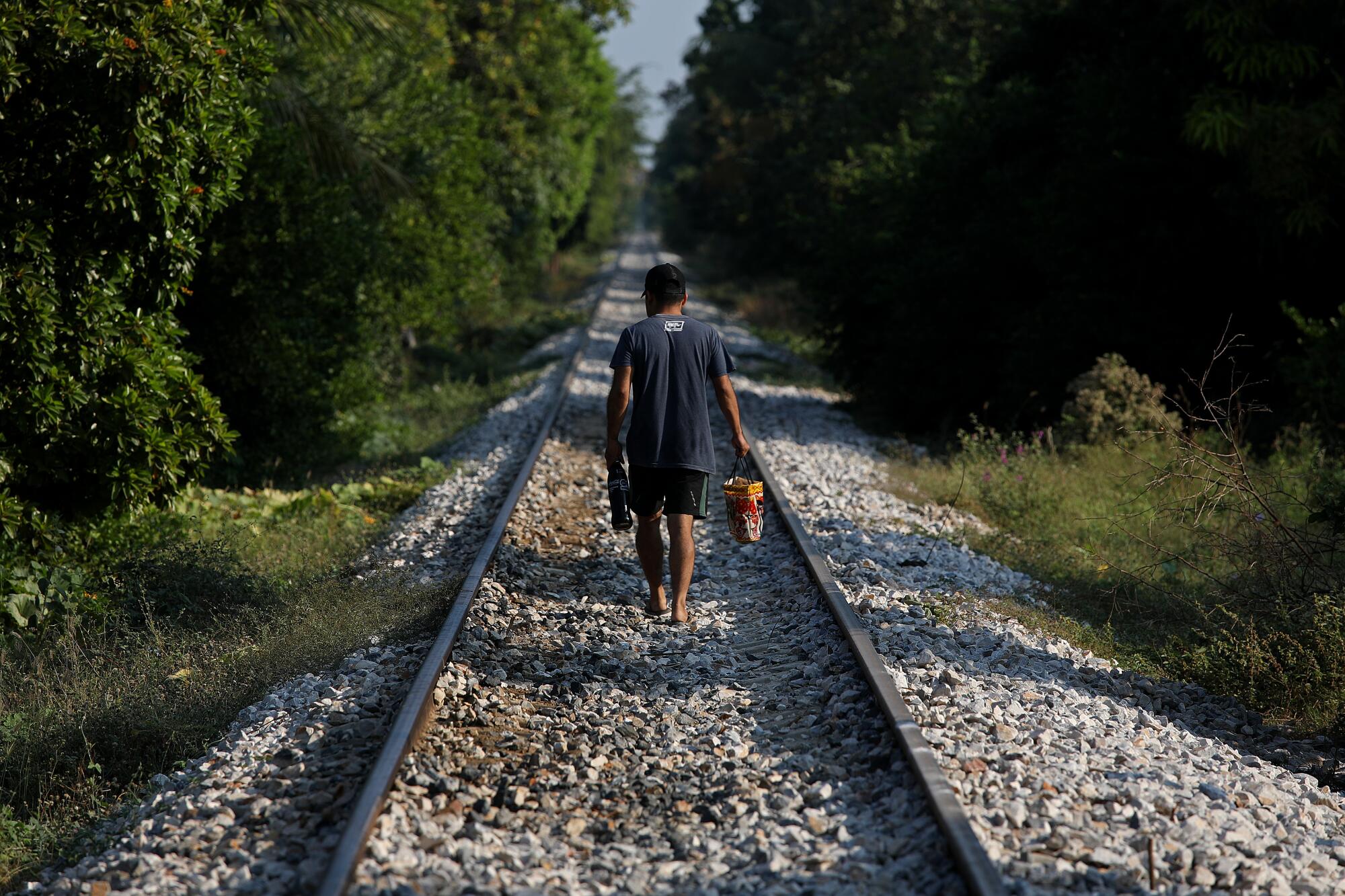 A man walks along the train tracks.