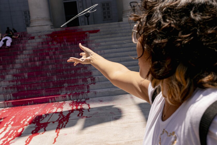 A person throws a hanger onto red-painted steps.