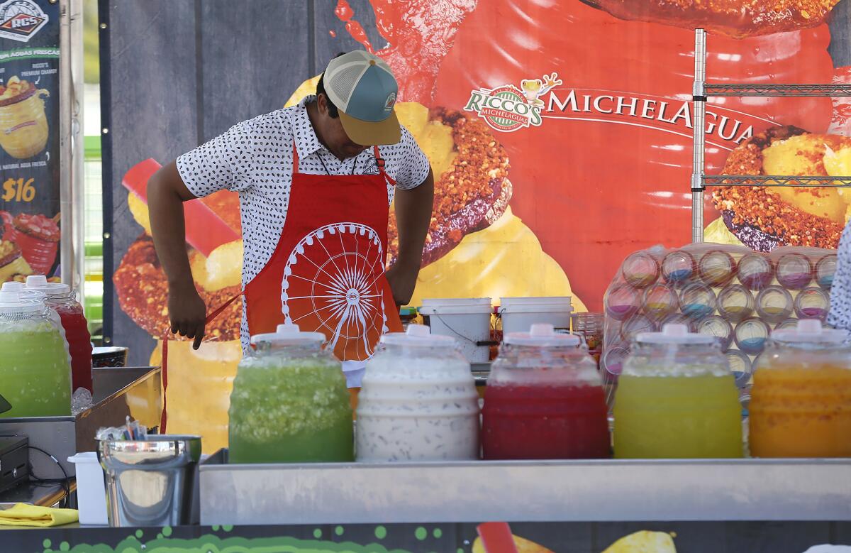 A fair worker puts on his apron at Ricco's Michelaguas on opening day of the 2023 Orange County Fair in Costa Mesa in July. 
