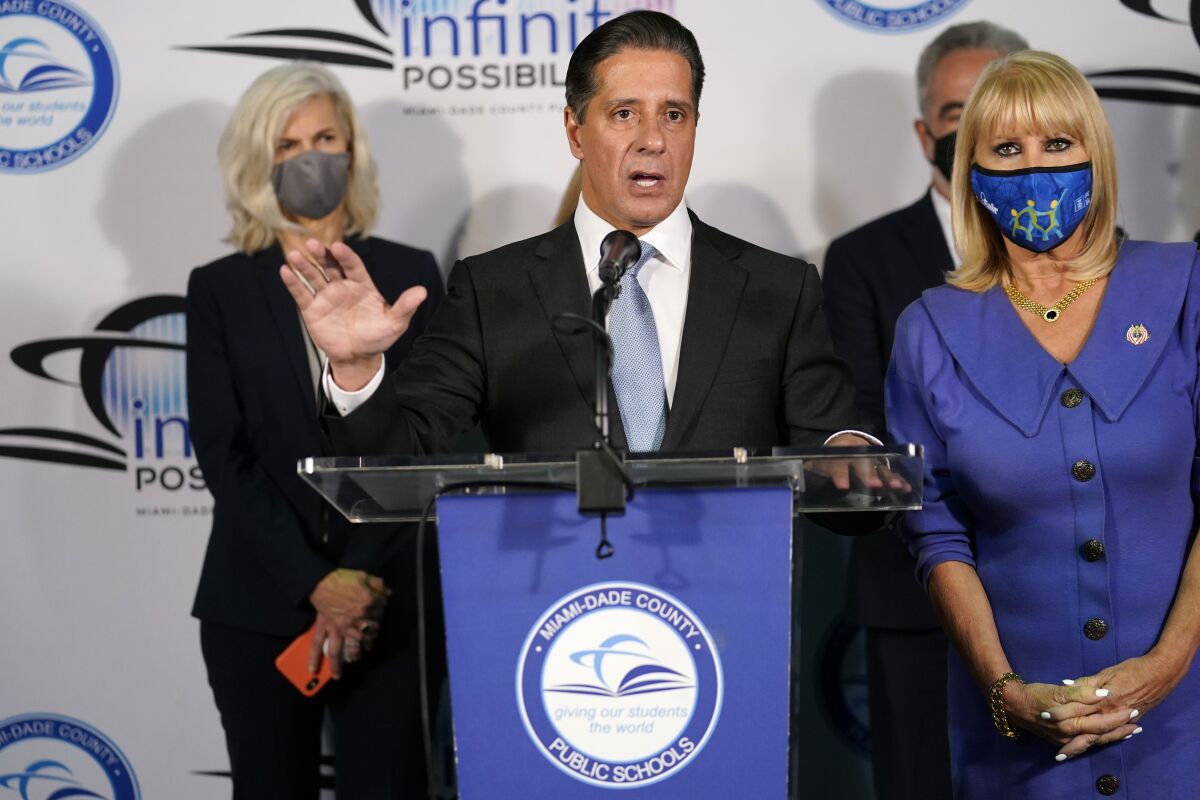 Miami-Dade County Public Schools Superintendent Alberto Carvalho stands with school board members as he announces at a news conference that wearing face masks to protect against COVID-19 will be optional in public schools, Tuesday, Nov. 9, 2021, in Miami. The new guideline will go into effect Friday. (AP Photo/Lynne Sladky)