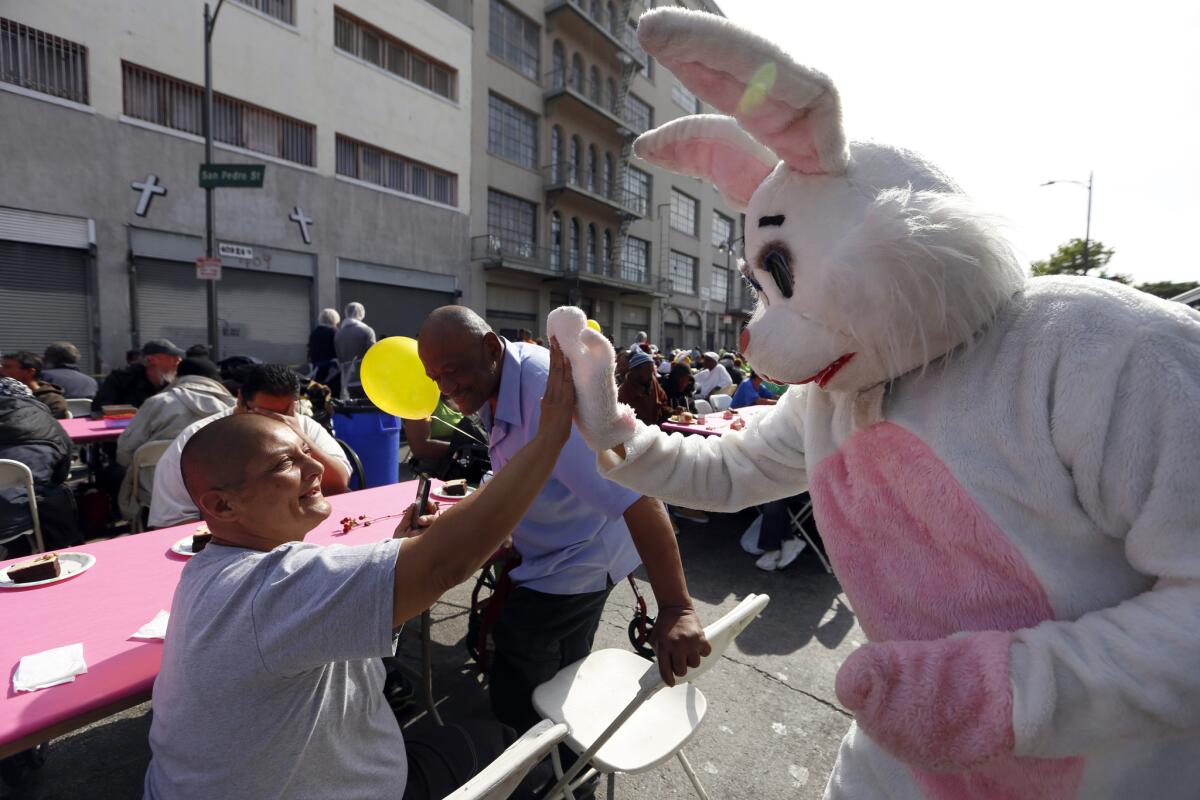 Dressed as the 'Easter Bunny,' Logan Hobson, 61, right, of Playa del Rey, gives a guest a high five. The Midnight Mission held a sit-down Easter brunch for homeless men, women and children.
