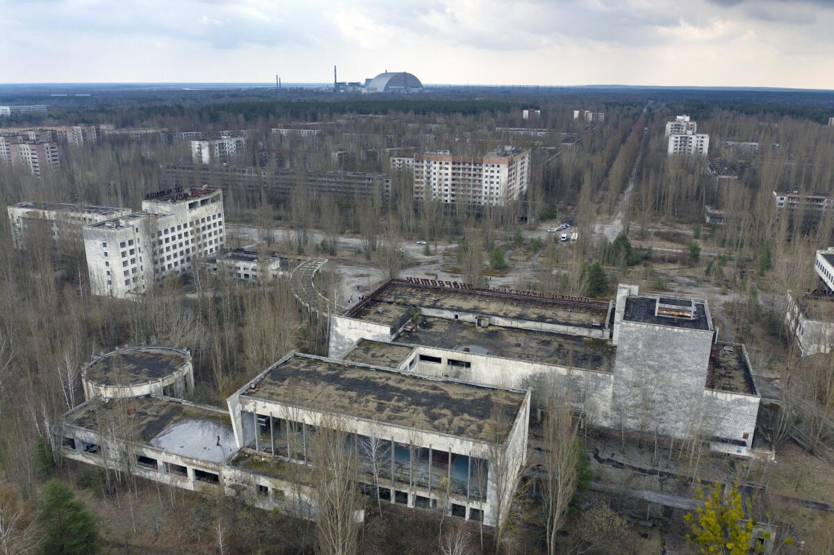 The ghost town of Pripyat with a shelter covering the exploded reactor at the Chernobyl nuclear plant in the background.