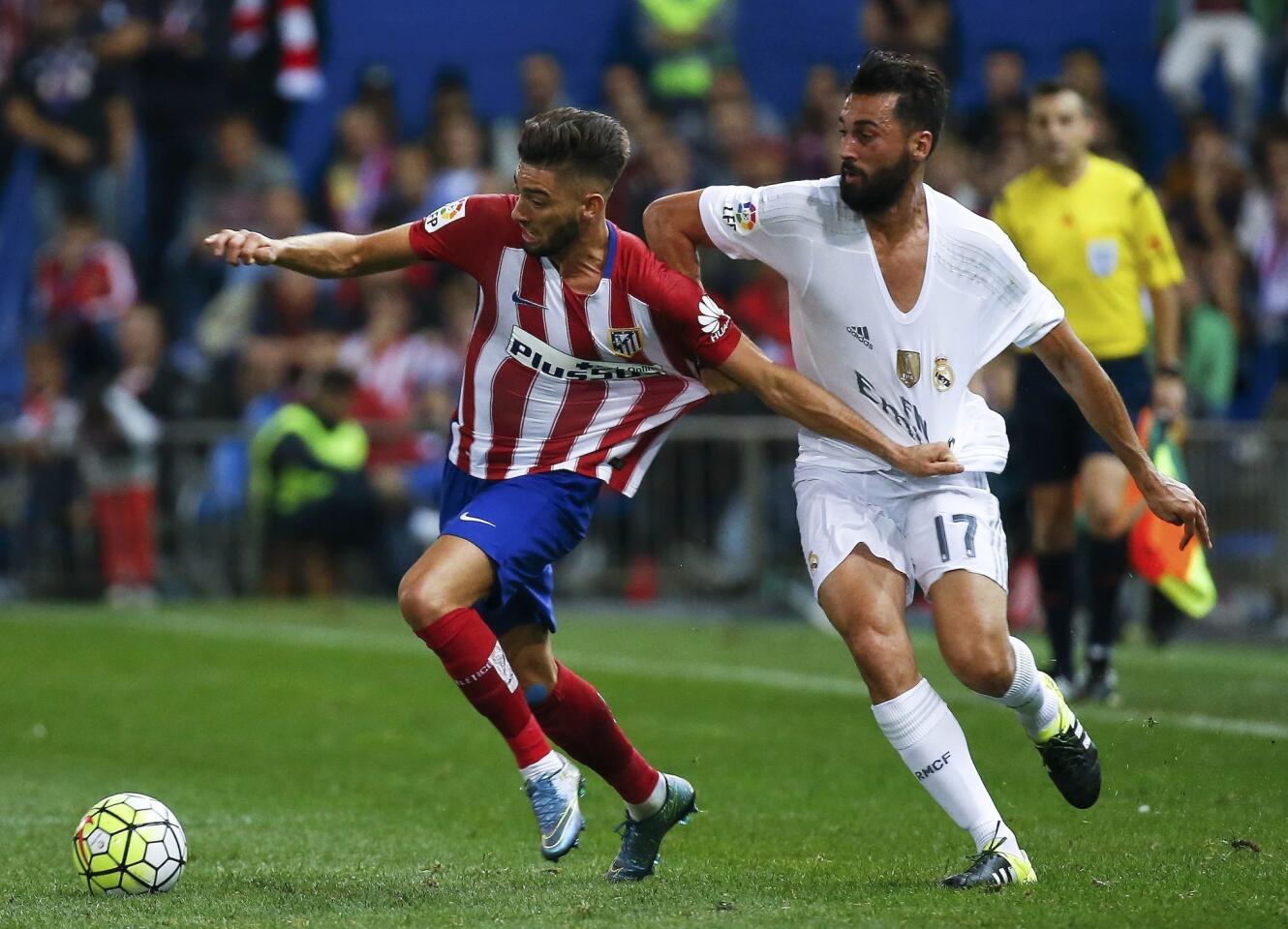 Atletico Madrid's Yannick Carrasco is challenged by Real Madrid's Alvaro Arbeloa during their Spanish first division derby soccer match in Madrid