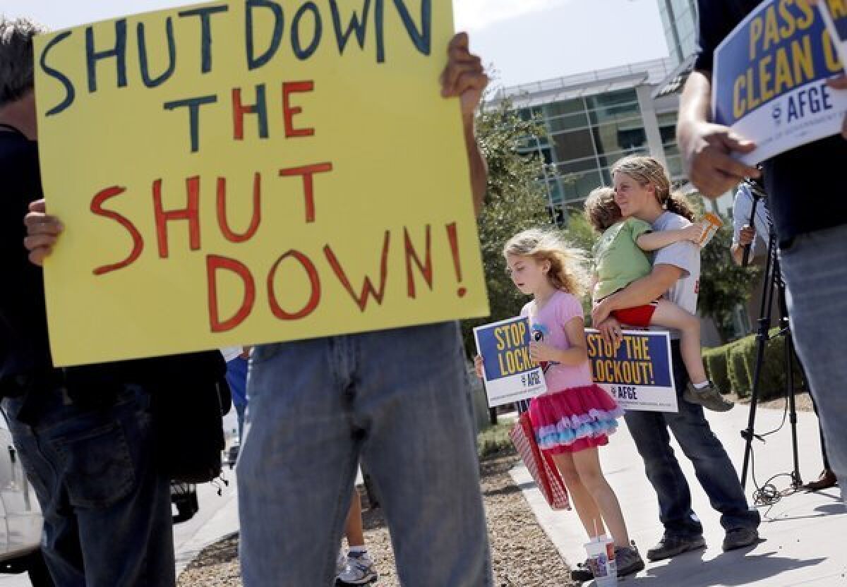 As the federal government shutdown continues, Tory Anderson, right, with her kids Audrey, 7, and Kai, 3, of Goodyear, Ariz., join others as they rally in front of the Social Security Administration offices in Phoenix.
