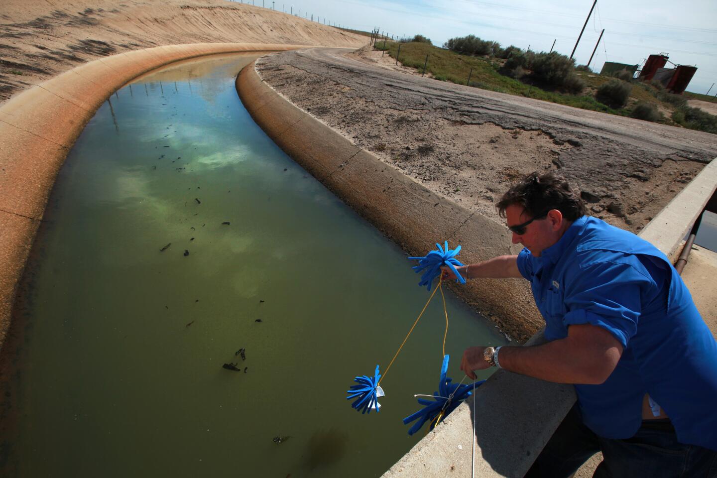 Scott Smith, chief scientist at Water Defense, deploys foam sponges to absorb test water from a canal operated by the Cawelo Water District near Bakersfield. The canal moves oil-produced water mixed with fresh water for use by Kern County farms.