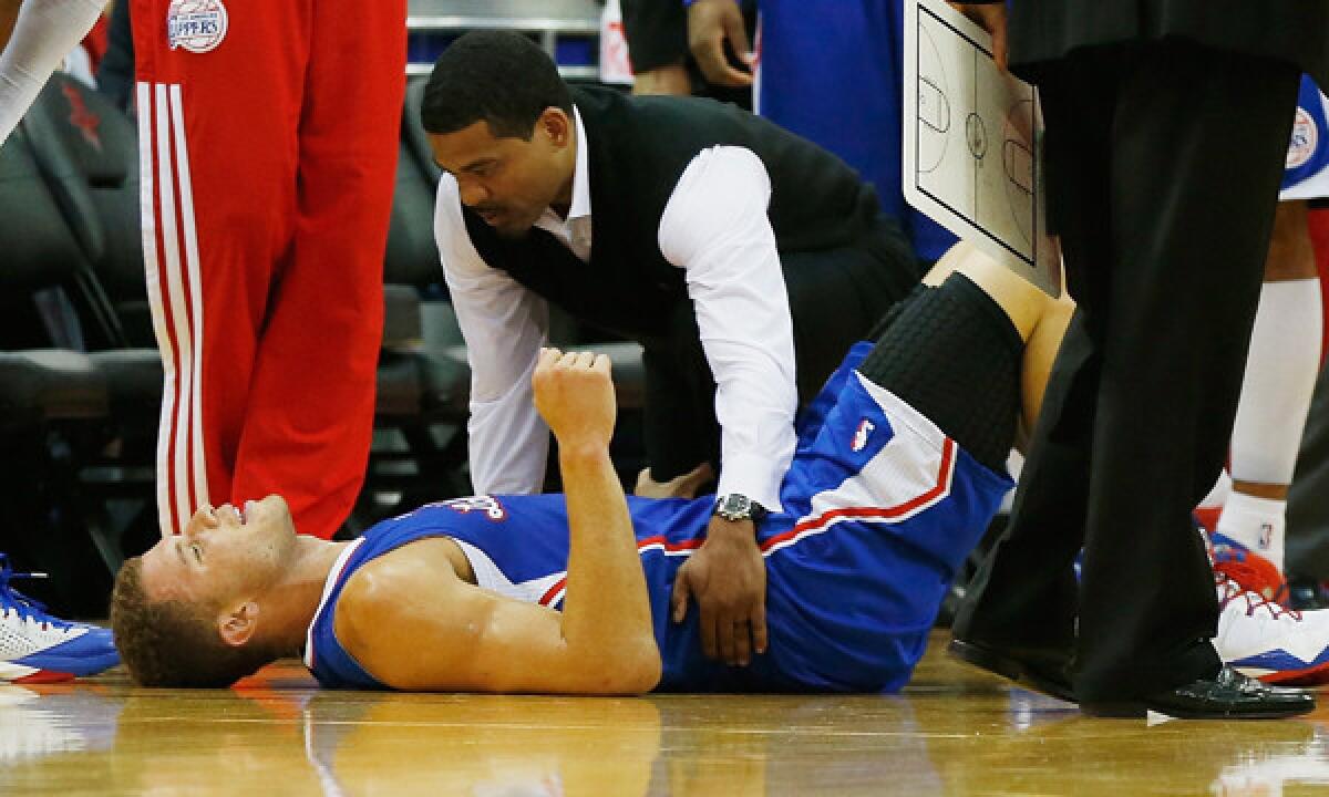 Clippers forward Blake Griffin is attended to by team trainer Jasen Powell after suffering a back spasm during the first half of Saturday's game against the Houston Rockets.