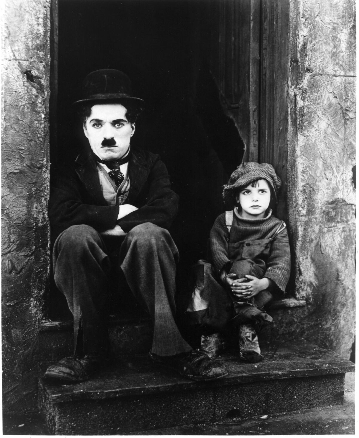 A black-and-white photo of a man and a child sitting on a stoop