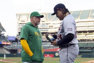 Oakland Athletics manager Mark Kotsay presents a bottle of wine to Detroit Tigers designated hitter Miguel Cabrera