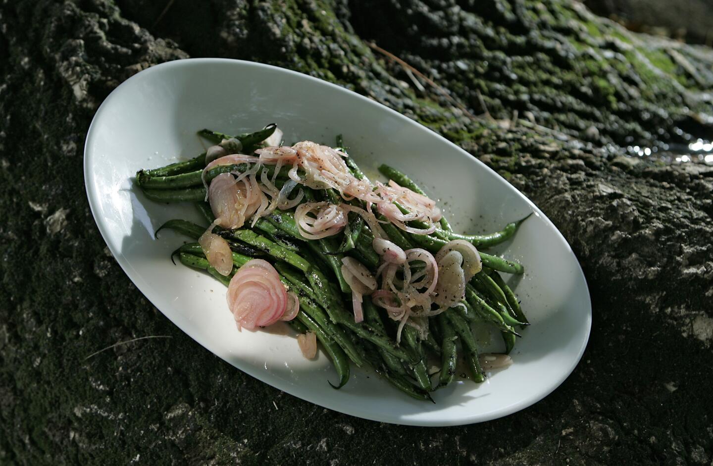 Green beans are quickly softened over the grill, the lightly charred beans dressed with olive oil, salt and tangy quick-pickled shallots.