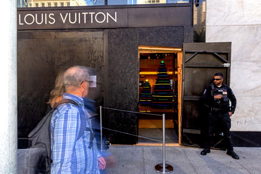 SAN FRANCISCO, CA - NOVEMBER 30: A security guard watches the entrance to a Louis Vuitton store, which has had its windows boarded near Union Square on November 30, 2021 in San Francisco, California. Stores have increased security in response to a spike in thefts. (Photo by Ethan Swope/Getty Images)