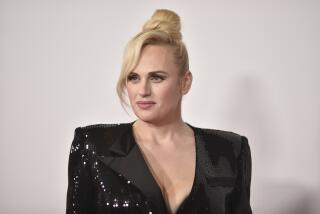 A woman with a bun of blond hair wearing a sparkly black blazer