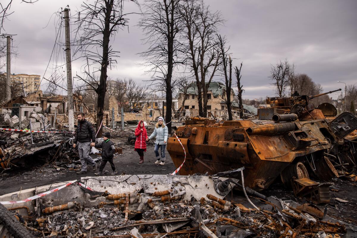 People walk outside amid destroyed military vehicles.