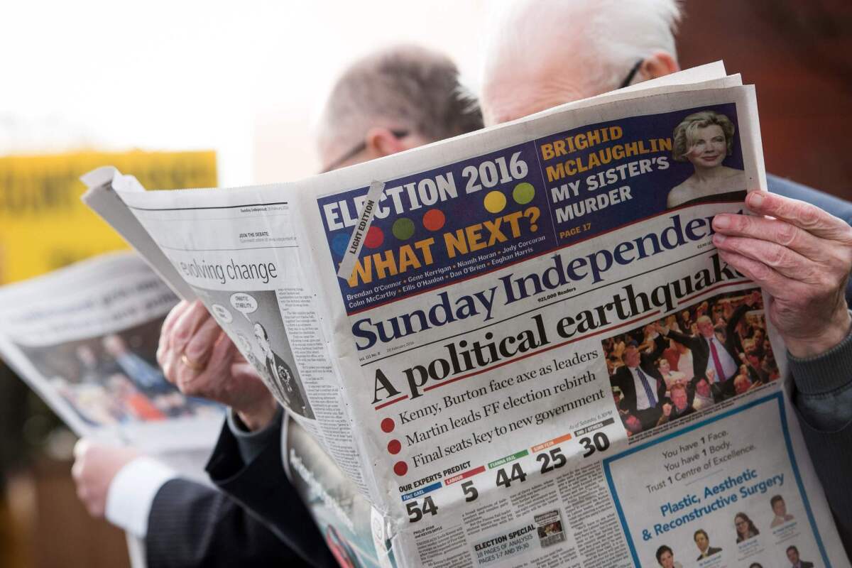 Fianna Fail party officials read the morning newspapers as they wait outside the count center in Dublin, Ireland, on Sunday.