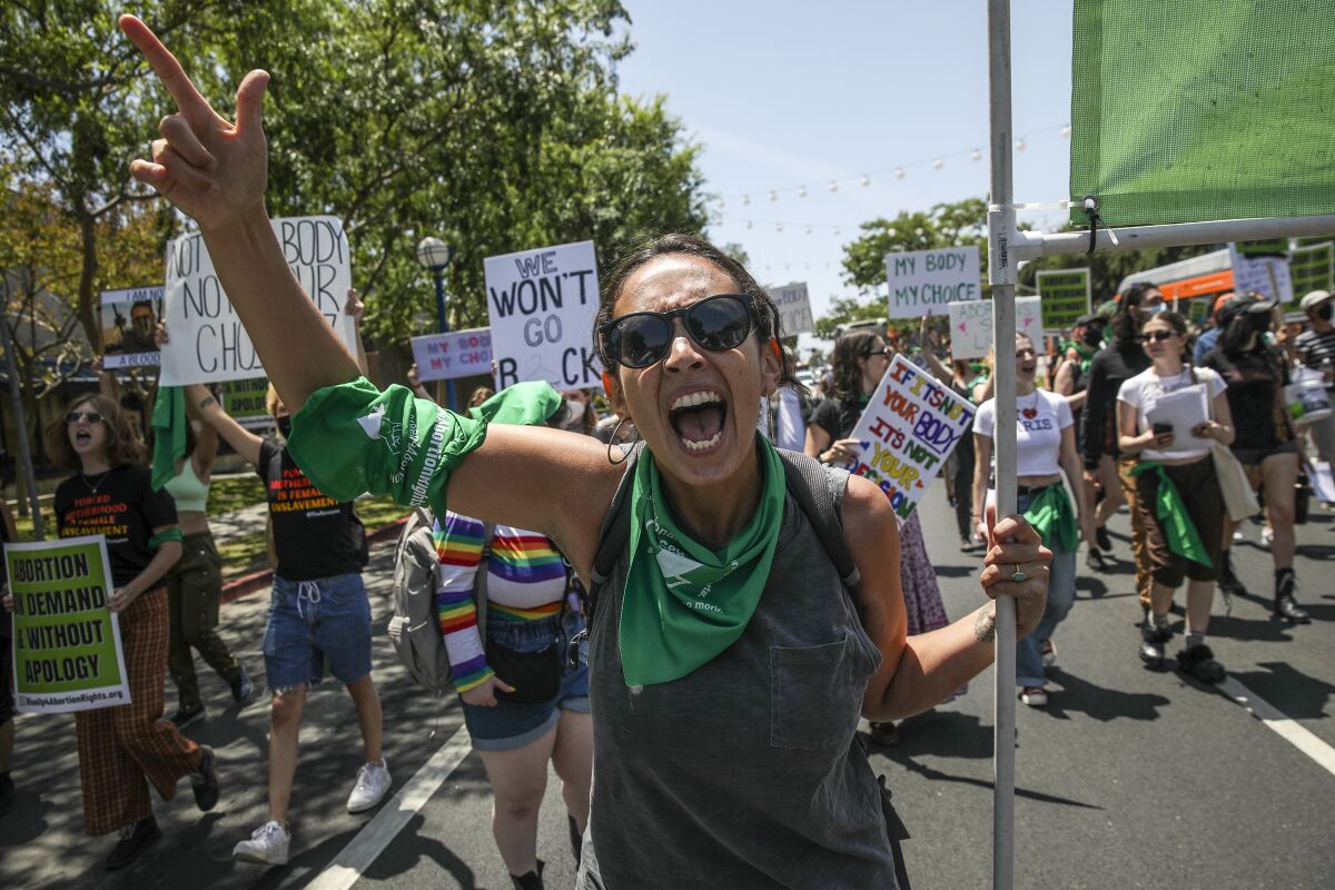 Micaela Bronstein and other abortion rights supporters march down a street holding signs