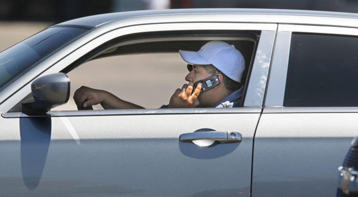 On the eve of a new California law requiring drivers to use hands-free cellphones, a motorist makes use of his handheld phone as he rolls along Rosecrans Avenue in San Diego.