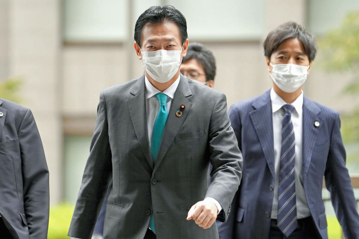 Tsukasa Akimoto, center, a member of the governing Liberal Democratic Party, arrives at Tokyo District Court in Tokyo Tuesday, Sept. 7 2021. The court on Tuesday convicted the ruling lamaker of taking bribes from a gaming company when he was serving vice-minister in charge of casino promotion, sentencing him to four years in prison in a high-profile case, an embarrassment to outgoing unpopular Prime Minister Yoshihide Suga’s party ahead of national elections later this year. (Kyodo News via AP)