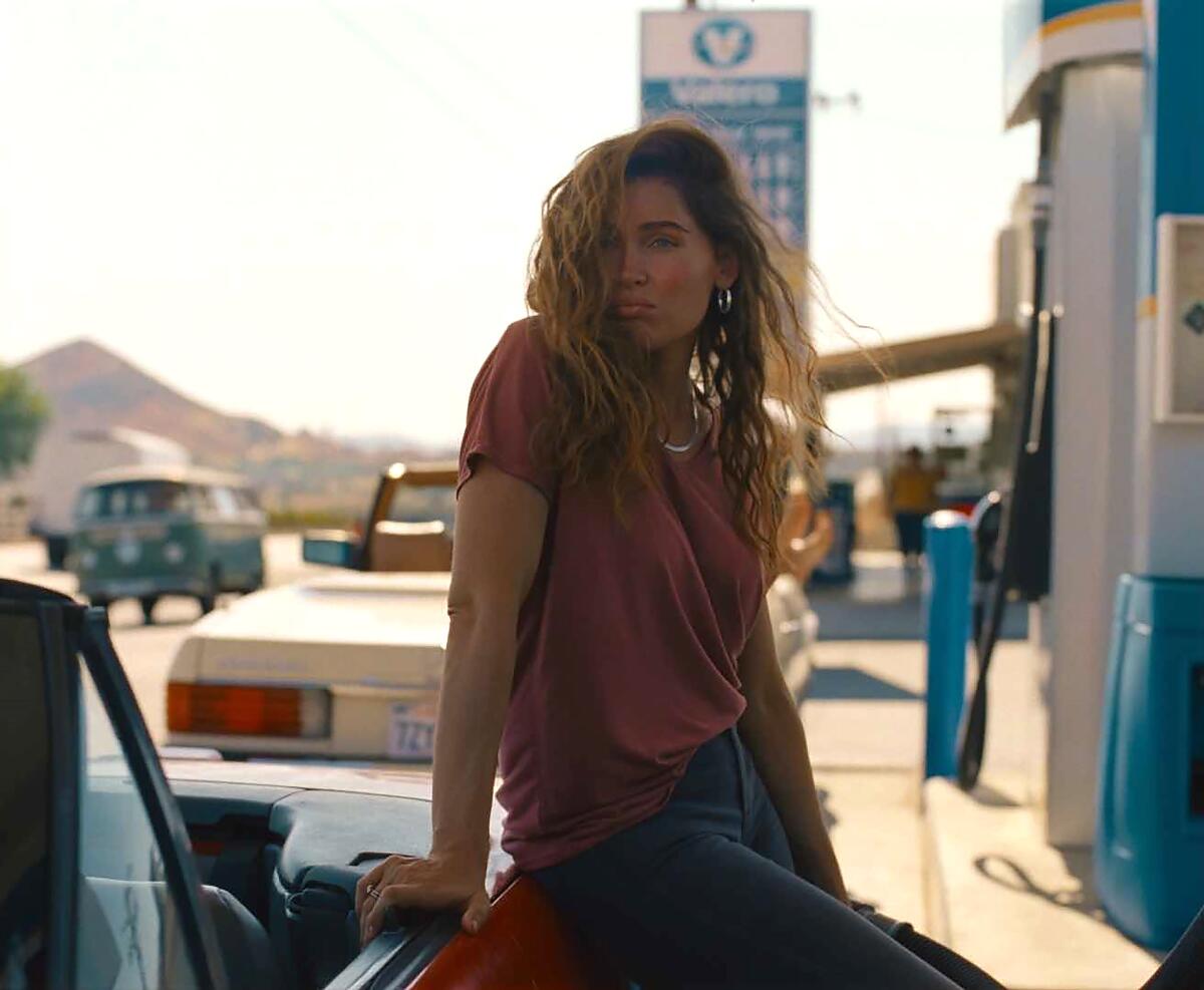 A woman leans against a car at a gas station in "Monica."