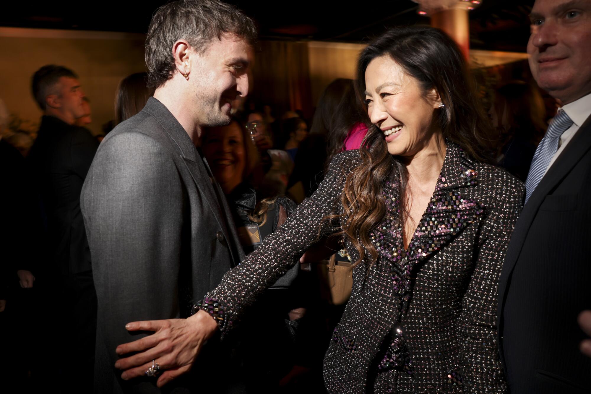 A woman pats a passing young man on his arm.