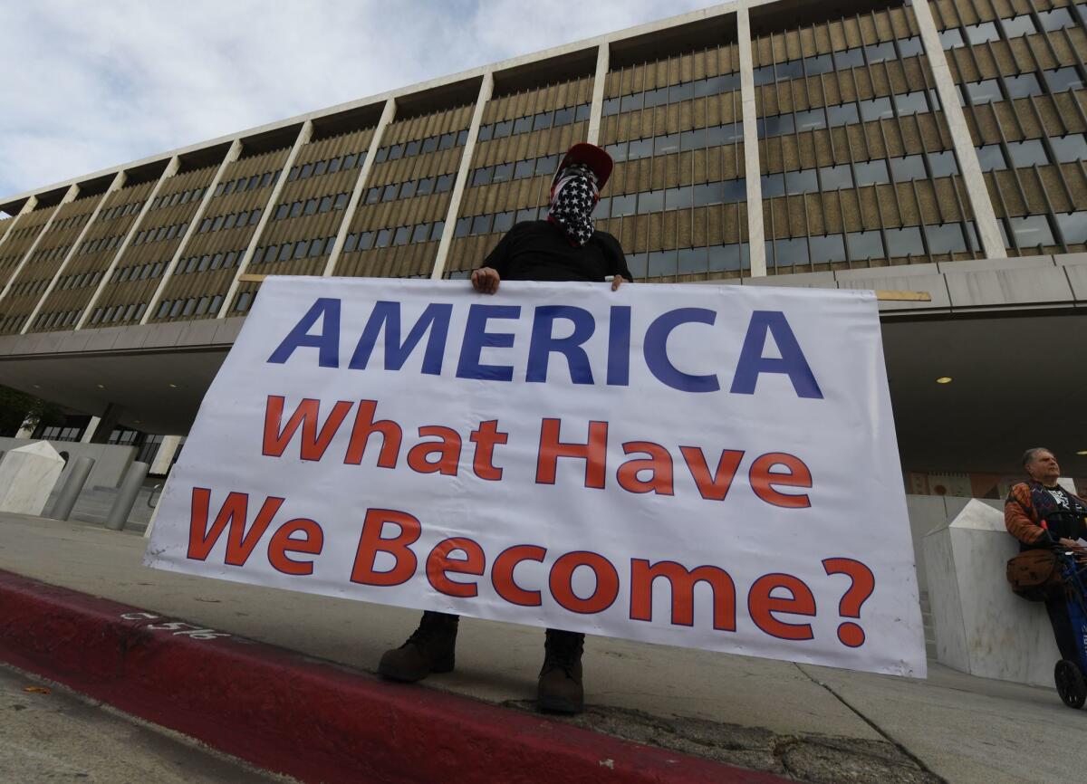 An immigrant rights activist holds a sign reading "America what have we become?" outside L.A. federal building in 2018