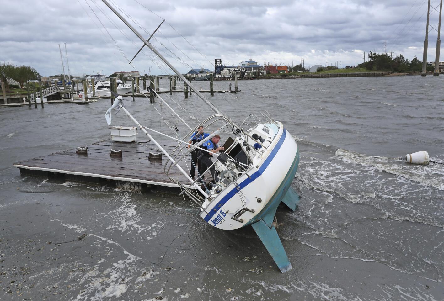 Beaufort Police Officer Curtis Resor, left, and Sgt. Micheal Stepehens check a sailboat for occupants in Beaufort, N.C. after Hurricane Dorian passed the North Carolina coast on Friday, Sept. 6, 2019. Dorian howled over North Carolina's Outer Banks on Friday — a much weaker but still dangerous version of the storm that wreaked havoc in the Bahamas — flooding homes in the low-lying ribbon of islands and throwing a scare into year-round residents who tried to tough it out. (AP Photo/Tom Copeland)