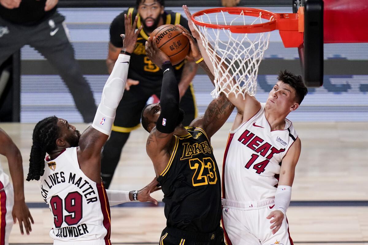 Los Angeles Lakers forward LeBron James scores between Miami Heat forward Jae Crowder, left, and guard Tyler Herro.