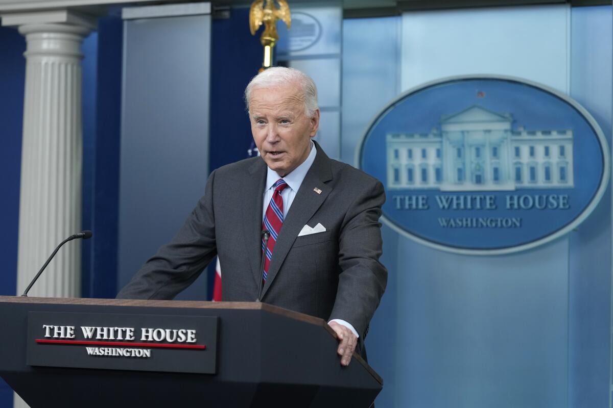 President Biden speaks at a lectern with a White House sign behind him 