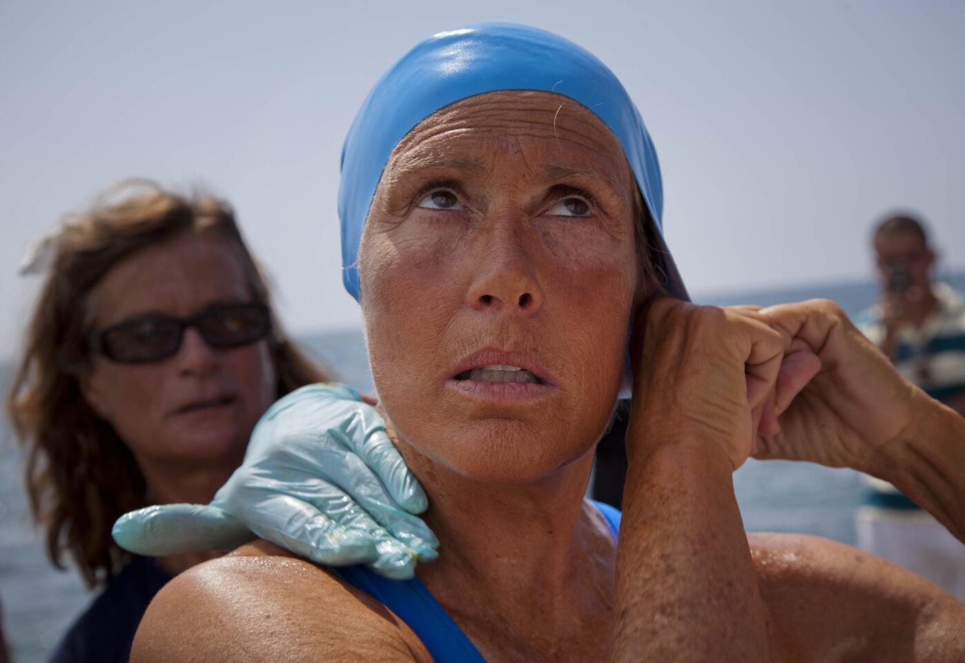 Diana Nyad adjusts her swimming cap as a woman applies a protective ointment to her skin as she prepares to start her attempt to swim to Florida from Havana, Cuba.