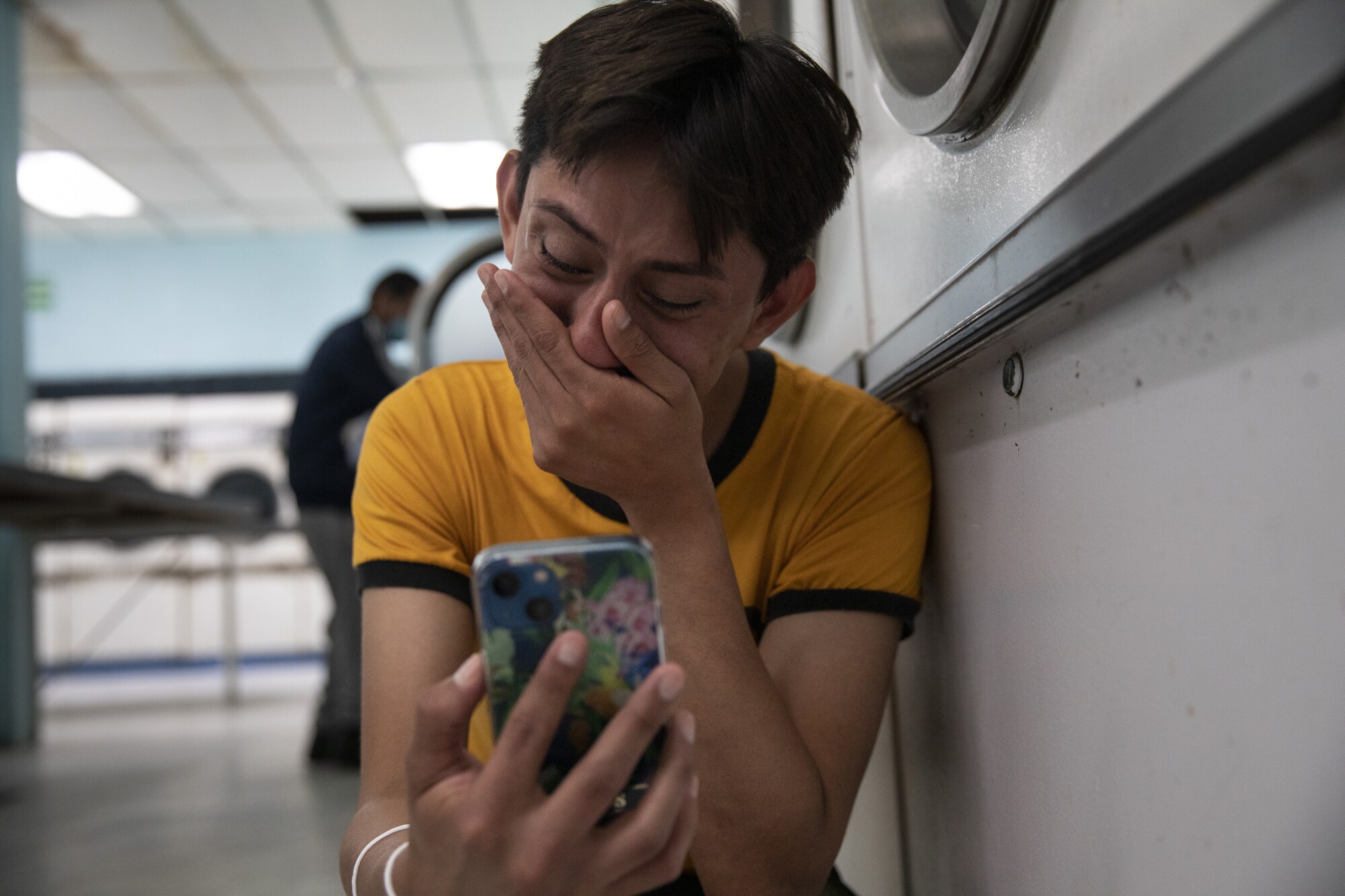 Ceidy Zethare leans on dryers in a laundromat as she calls her mother after learning that she will be allowed into the U.S.
