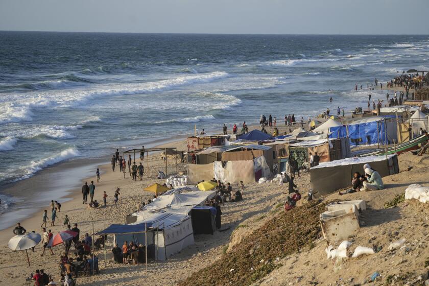 Palestinians displaced by the Israeli air and ground offensive on the Gaza Strip walk along a beach of Mediterranean Sea at a makeshift tent camp in Deir al Balah, Monday, May 13, 2024. Palestinians on Wednesday, May 15, 2024, will mark the 76th year of their mass expulsion from what is now Israel. It's an event that is at the core of their national struggle, but in many ways pales in comparison to the calamity now unfolding in Gaza. (AP Photo/Abdel Kareem Hana)