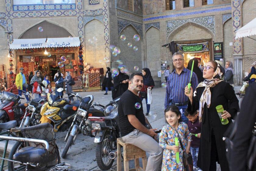 Iran - Isfahan (Esfahan), capital of the province of the same name, evening scene at the entrance to the Royal Bazaar (Bazar Qeisarieh) on the north side of the Imam Square. A girl and several men watch the colorful soap bubbles that make a woman rise. Taken on 25.10.2018. Photo by: Rolf Zimmermann/picture-alliance/dpa/AP Images