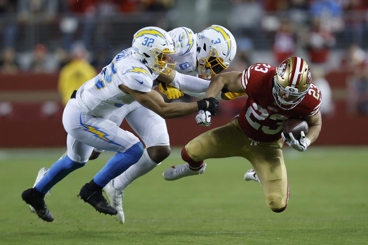 49ers running back Christian McCaffrey runs by Chargers Alohi Gilman and Derwin James Jr. 