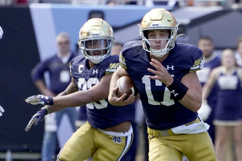 Notre Dame quarterback Jack Coan carries the ball during the first half.